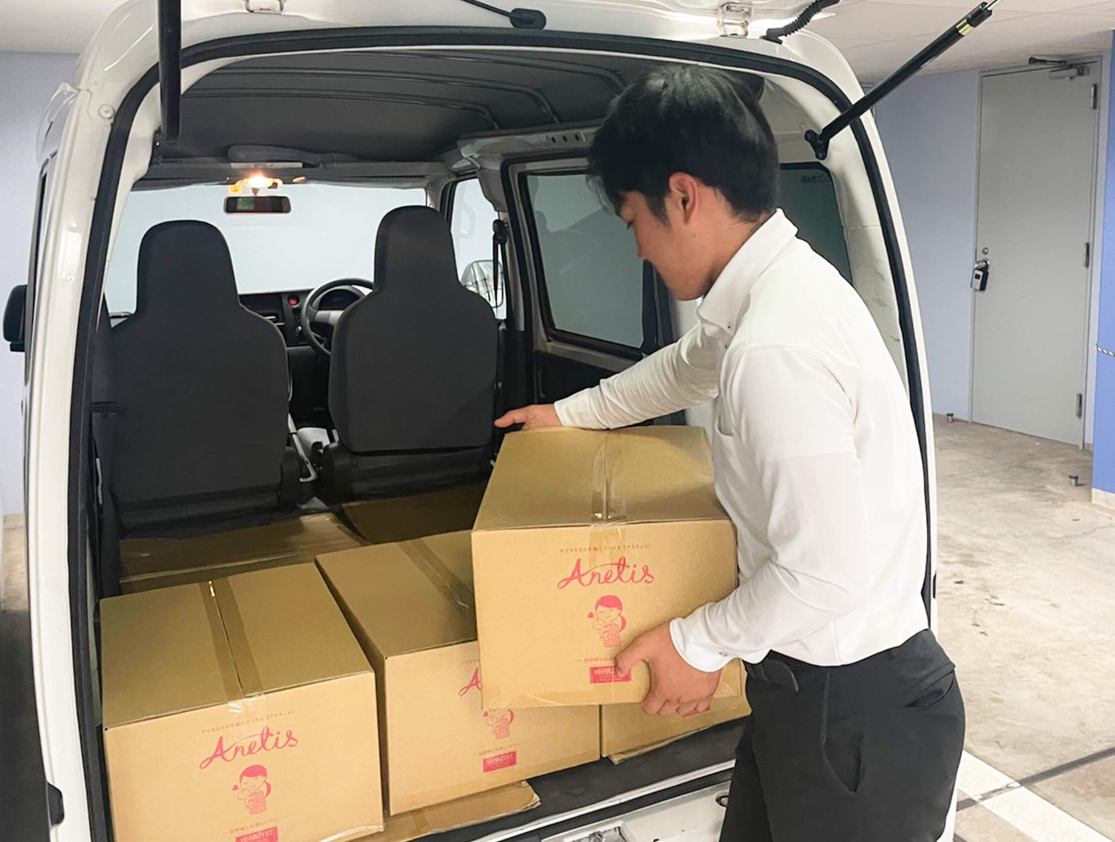 車の荷台にAnetisお土産バッグの入ったダボールを積むスタッフ